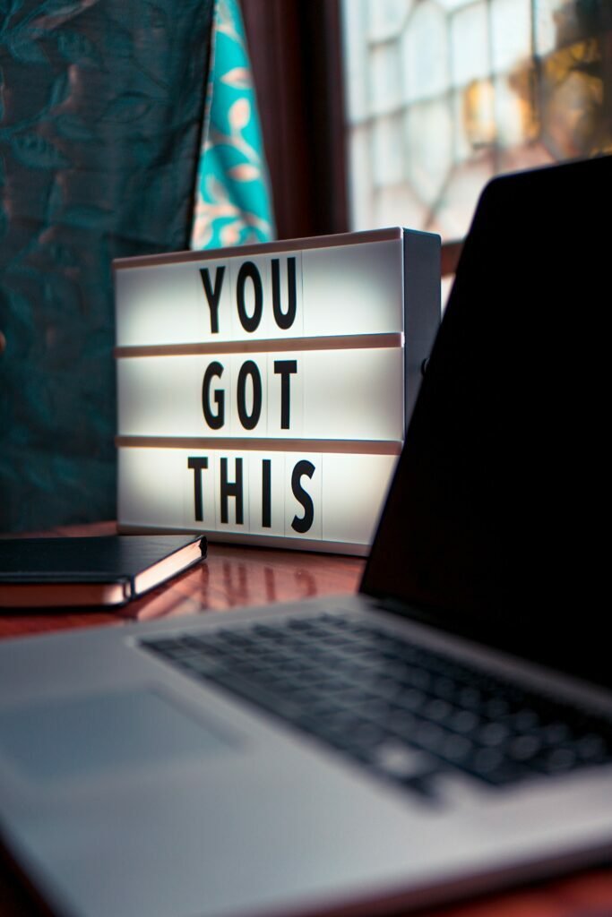 A lit-up sign on a computer desk in front of a window, reading "You Got This".